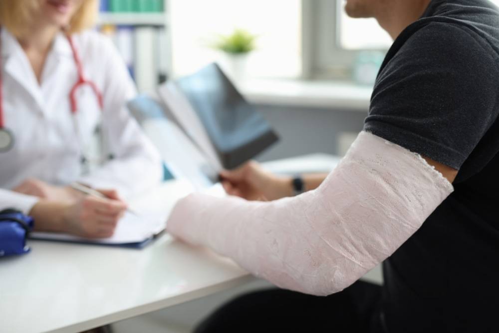Doctor conducts medical consultation with patient with cast on arm. Hand fracture and treatment