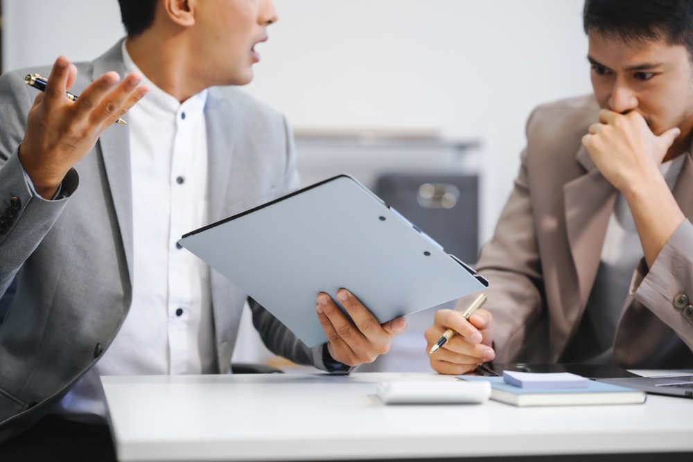Two businessmen argue in the modern workplace after making a mistake. They discuss poor performance
