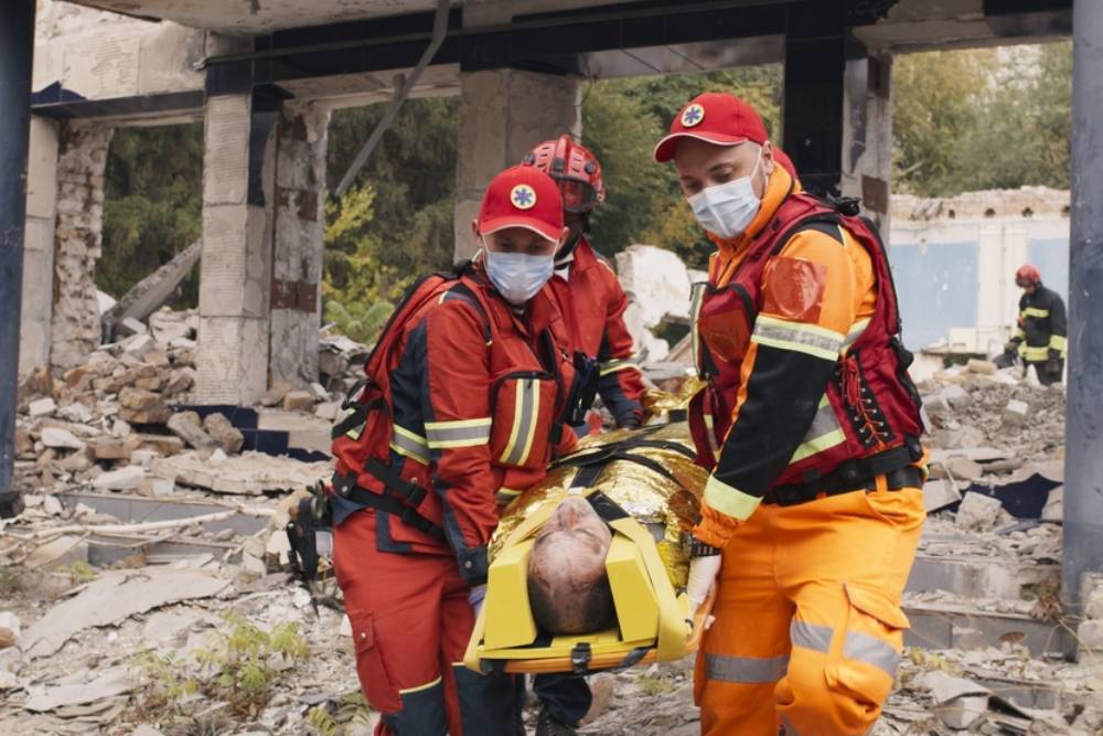 Diverse paramedics carrying survivor to van