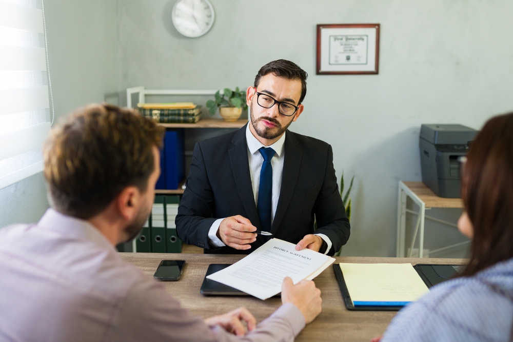 Lawyer explaining documents to a married couple at an office meeting concerning a divorce agreement